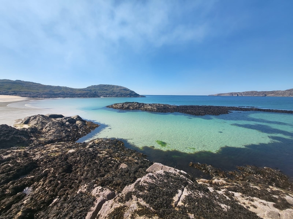 Vue panoramique d'une plage immaculée avec une eau bleue claire et des rochers