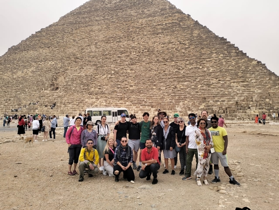 Group of tourists posing in front of a pyramid.