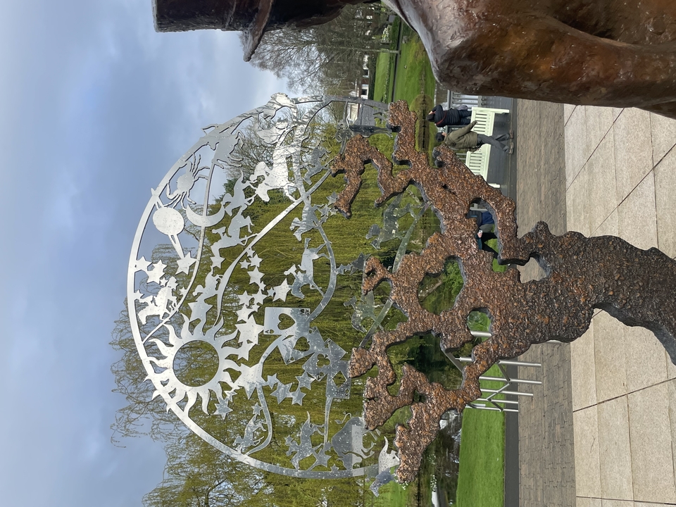 Sculpture made of metal shaped like trees and a globe.