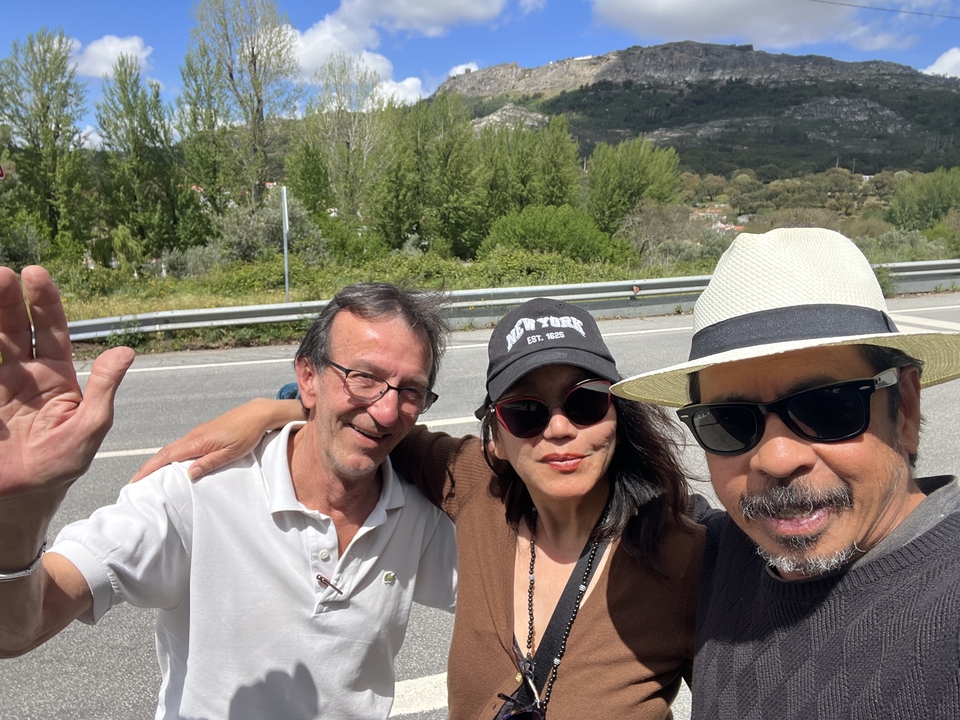 Three people smiling with a road in the background.