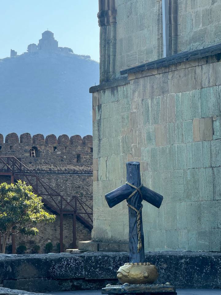 A stone cross with mountains in the background.