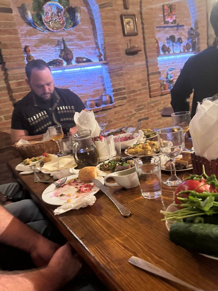 A group of people dining with a table full of food.