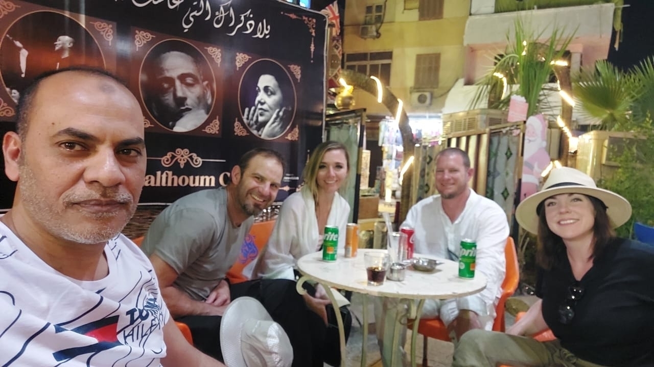 Groupe de personnes assises à une table de café en plein air.