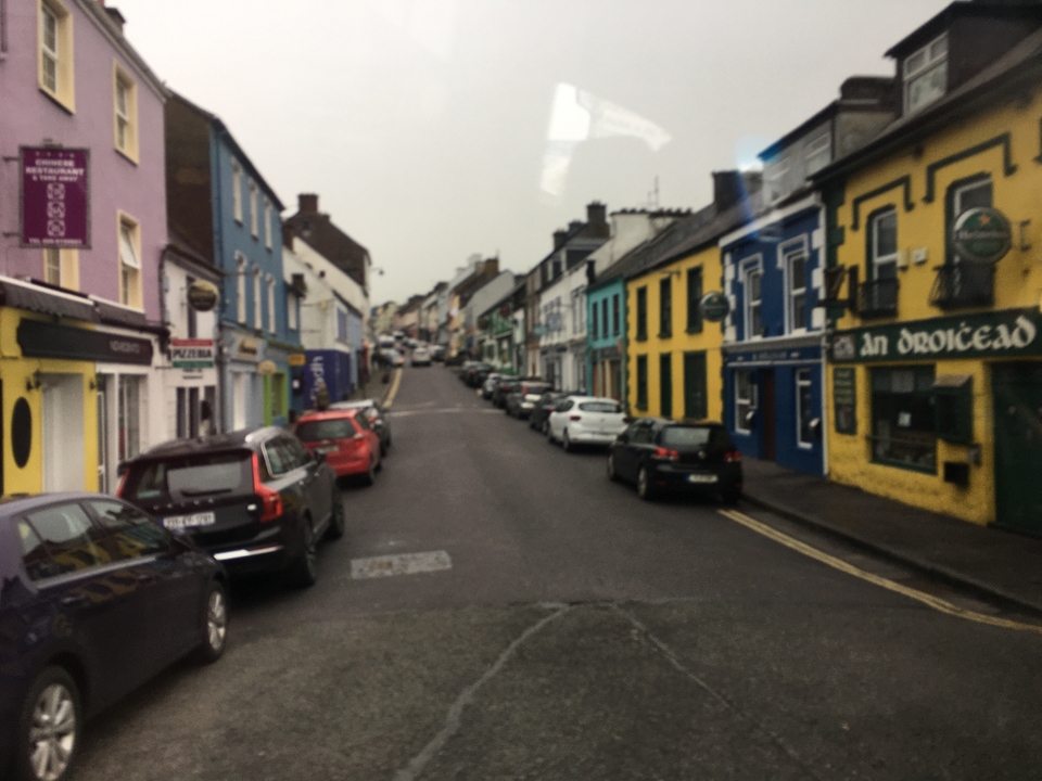 Vue de rue d'immeubles colorés avec des voitures garées.
