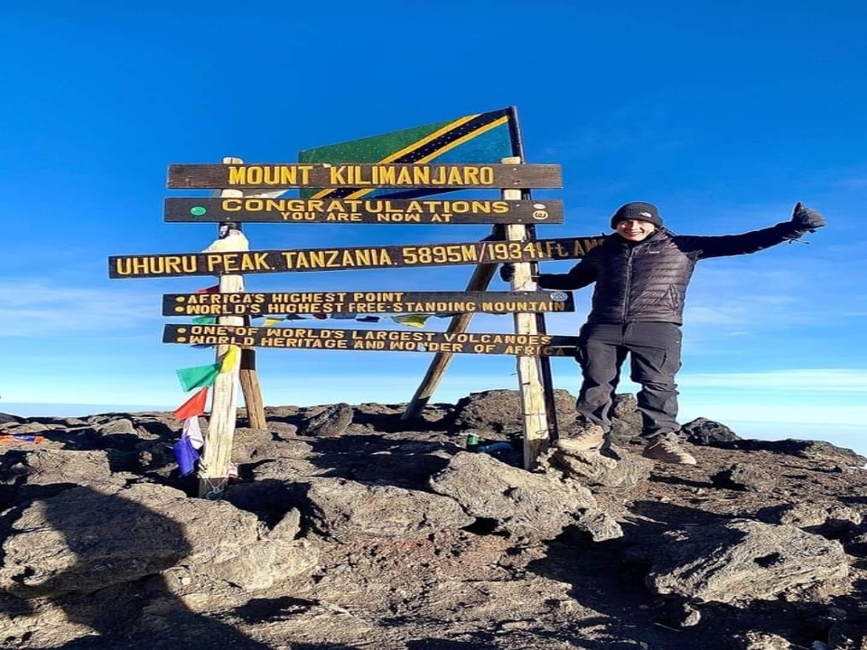 Randonneurs célébrant au sommet d'Uhuru Peak avec un panneau de sommet.