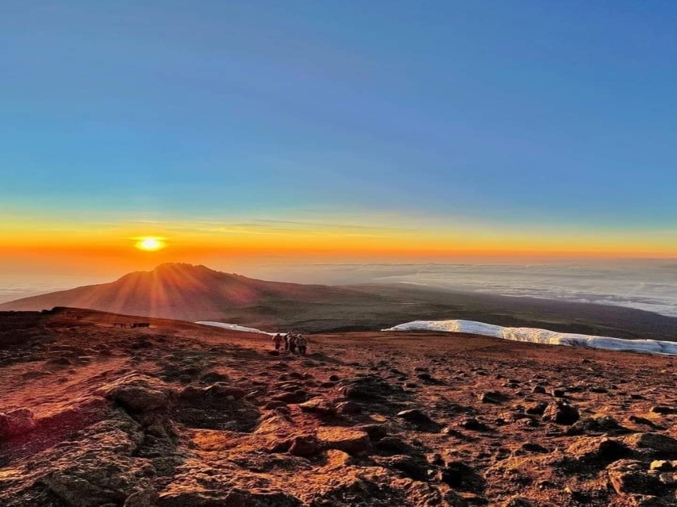 Vue panoramique d'un lever de soleil sur des montagnes enneigées.