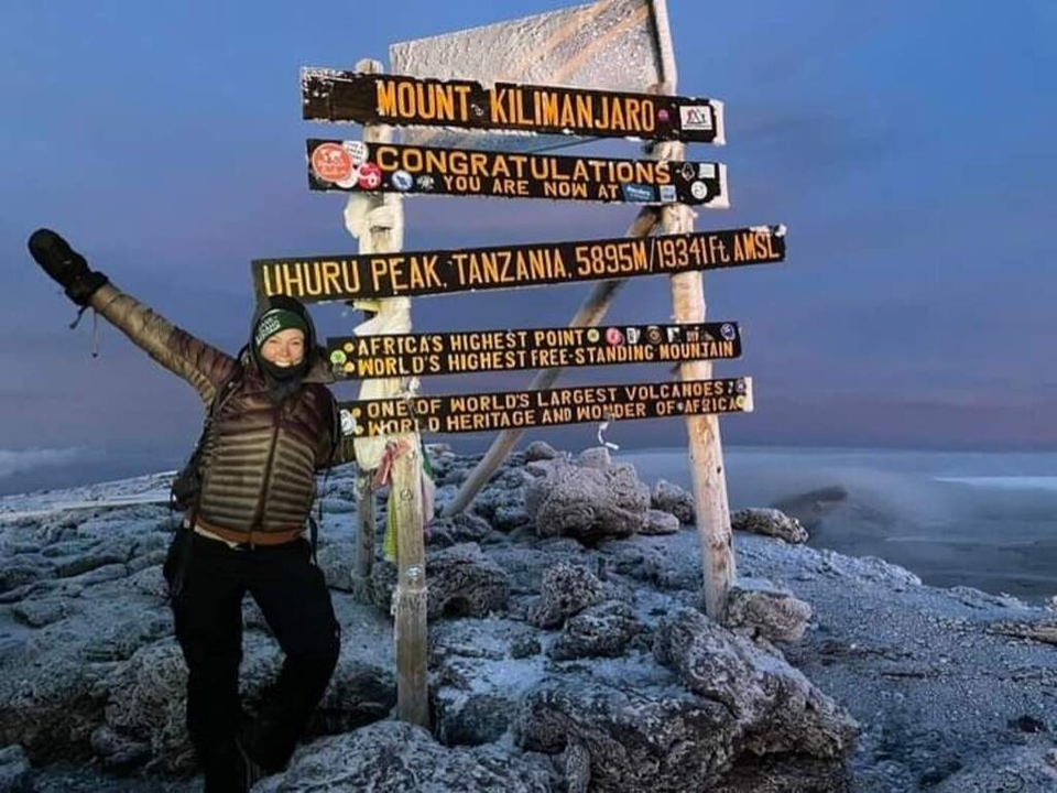 Grimpeur au pic Uhuru avec panneau indicateur et lever de soleil.