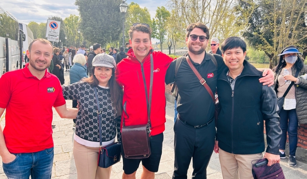 Group of people posing outdoors with a sign in the background.