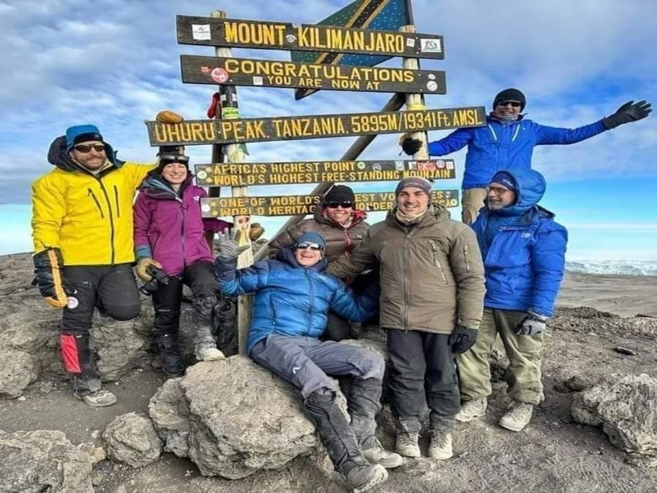Groupe de grimpeurs au sommet d'Uhuru avec panneau indicateur.