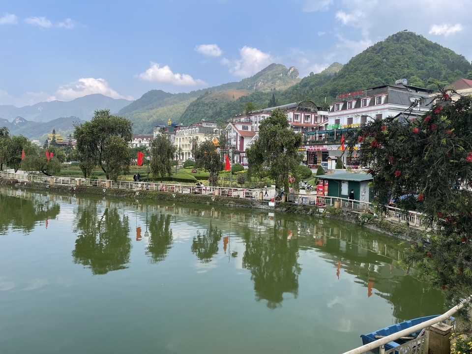 Cityscape with colourful buildings reflecting in a lake.