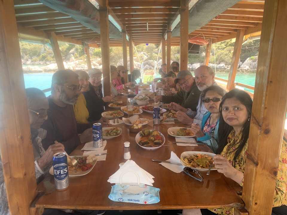 Group dining on a boat with scenic views outside.