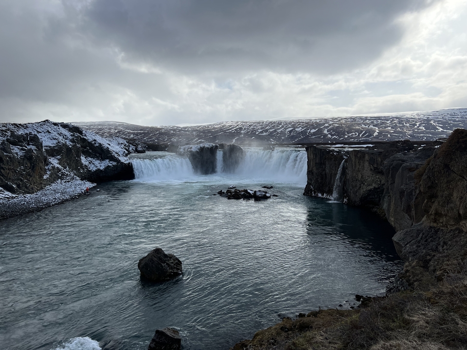 A wide waterfall with surrounding rugged landscape.