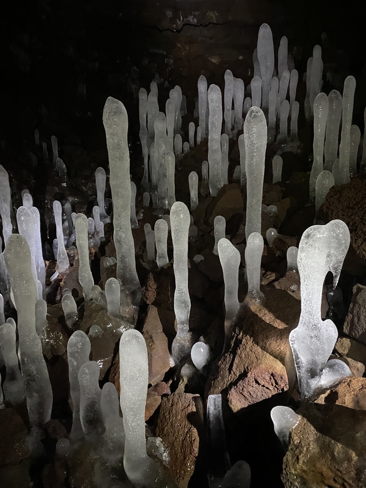 Formations de glace dans une grotte avec des structures semblables à des stalagmites et des rochers.