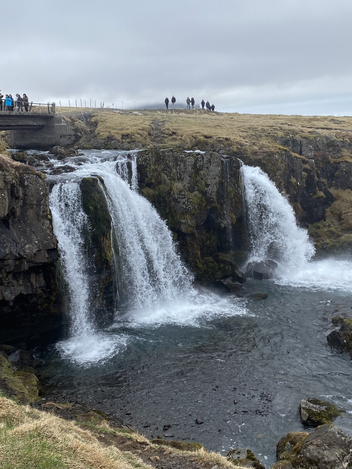 Une petite cascade à plusieurs niveaux entourée de falaises rocheuses.