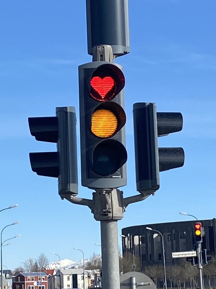 Un feu de circulation avec des signaux rouge et jaune illuminés sur fond de ciel bleu.