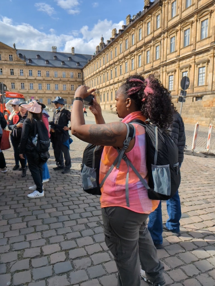 Une femme prenant des photos dans une rue pavée d'une zone urbaine.