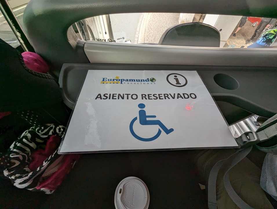 Un panneau de siège réservé avec un symbole de handicap, placé à l'intérieur d'un véhicule.