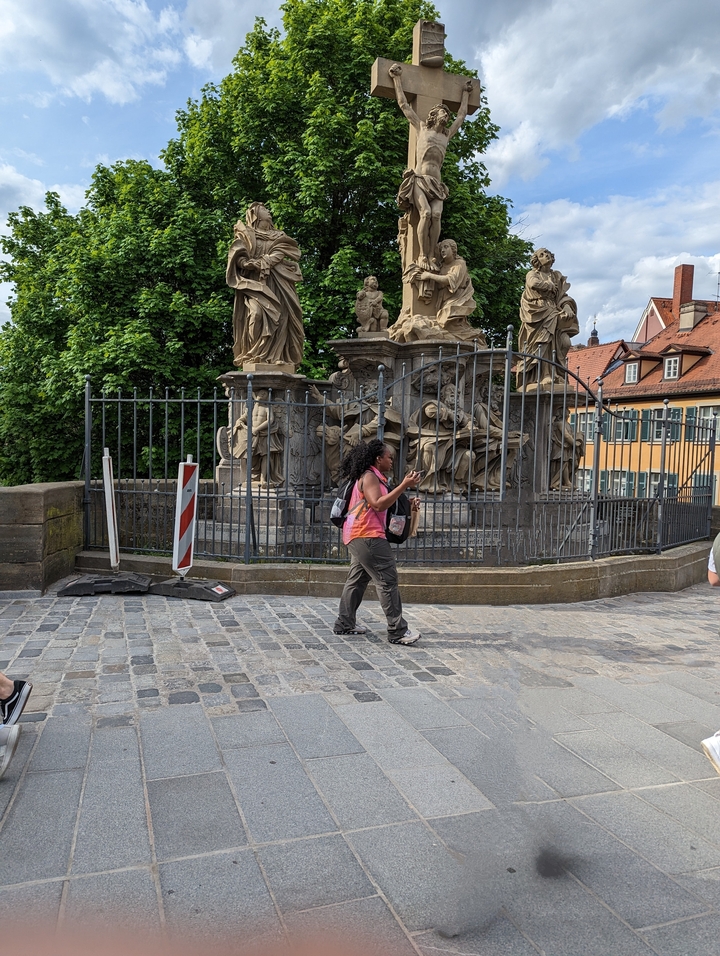 Une femme passant devant une statue historique dans une zone clôturée.
