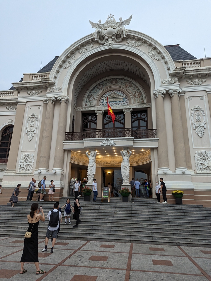 Opera House with a flag and many visitors.