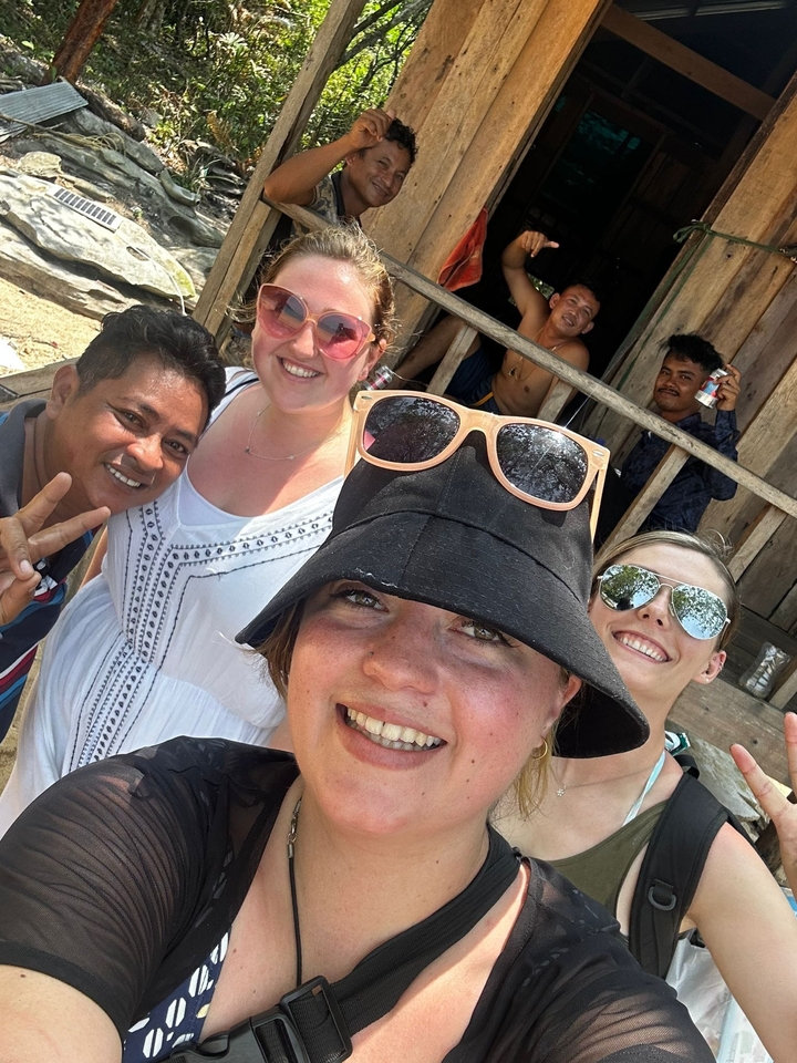Group of friends taking a selfie with smiles and peace signs.