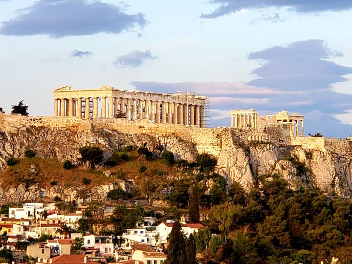 The Acropolis structure during sunset with lit buildings.