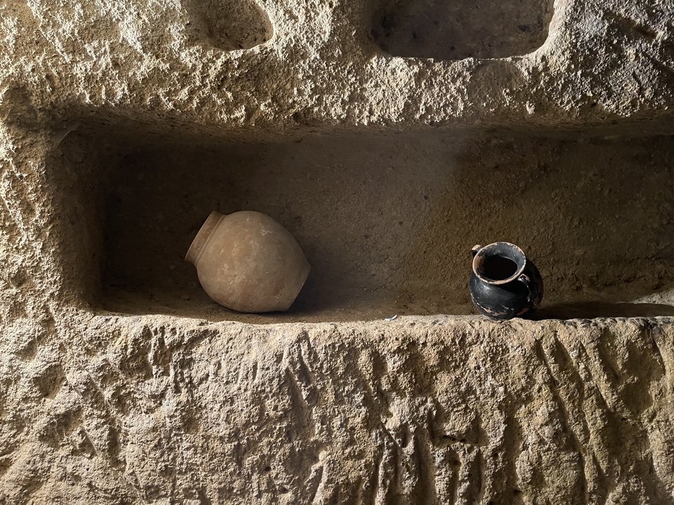 Ancient pottery displayed in a rocky niche, possibly in a cave.