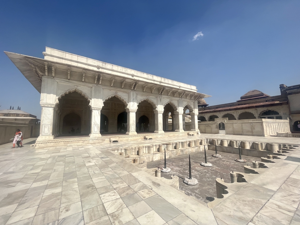 Historic building with arches and courtyard in bright sunlight.