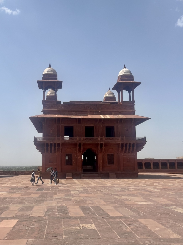 Historic red sandstone building with people touring.