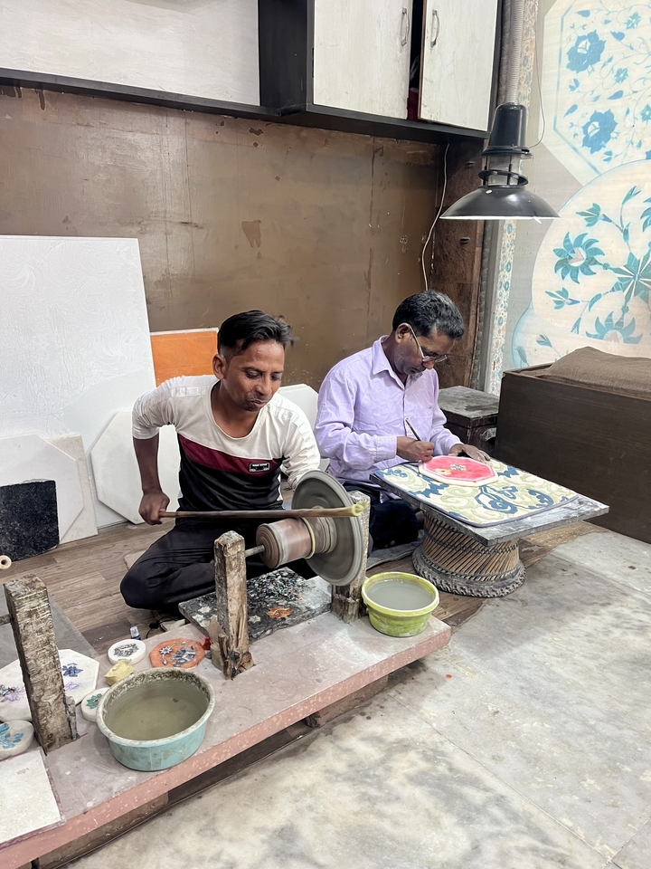 Two artisans working on crafting details.