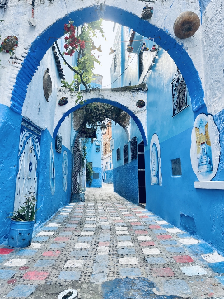 Narrow street with blue painted walls and arches.