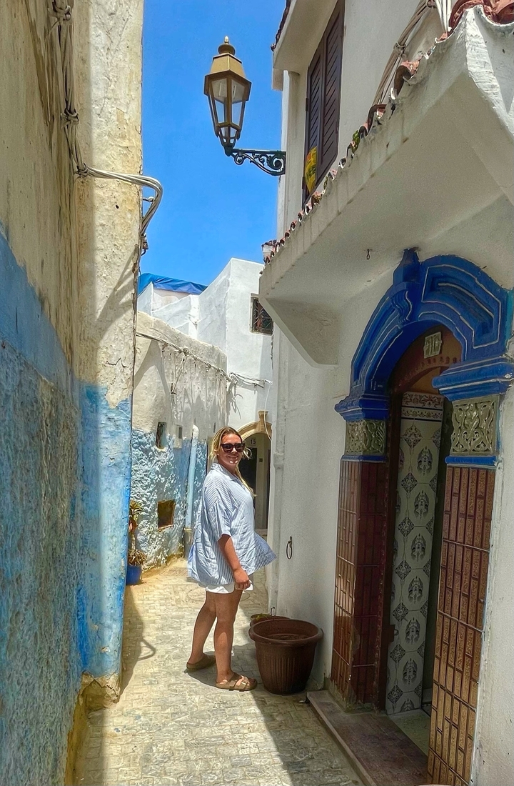 Woman standing in a narrow alley with colorful doors.