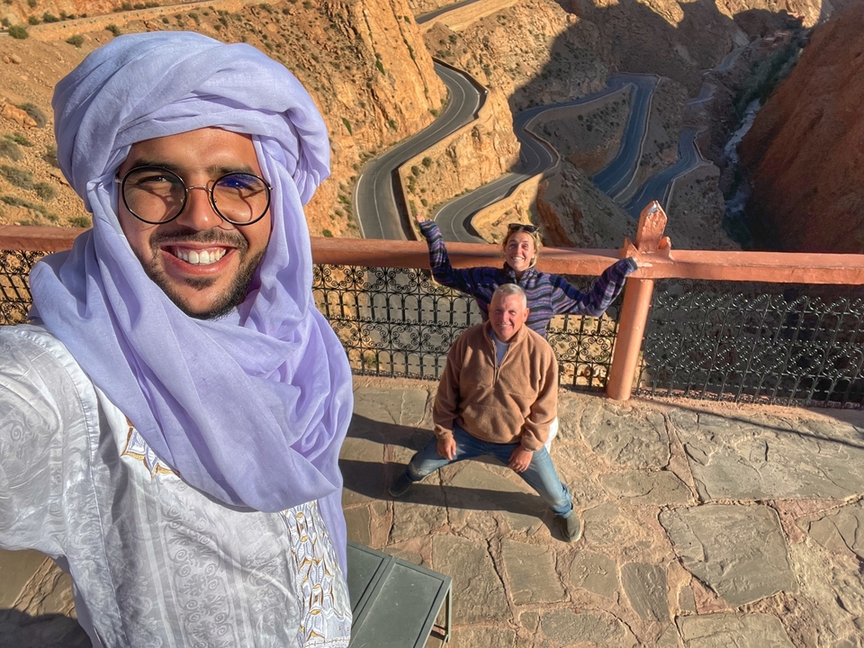People standing at a viewpoint overlooking a winding mountain road.