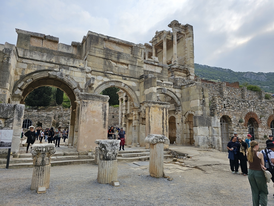 Des visiteurs explorant des ruines antiques avec des colonnes et des arches.