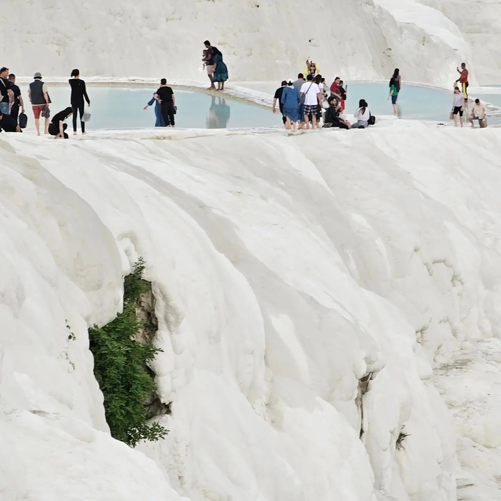 Terrasses de travertin blanc avec des gens qui explorent au sommet.