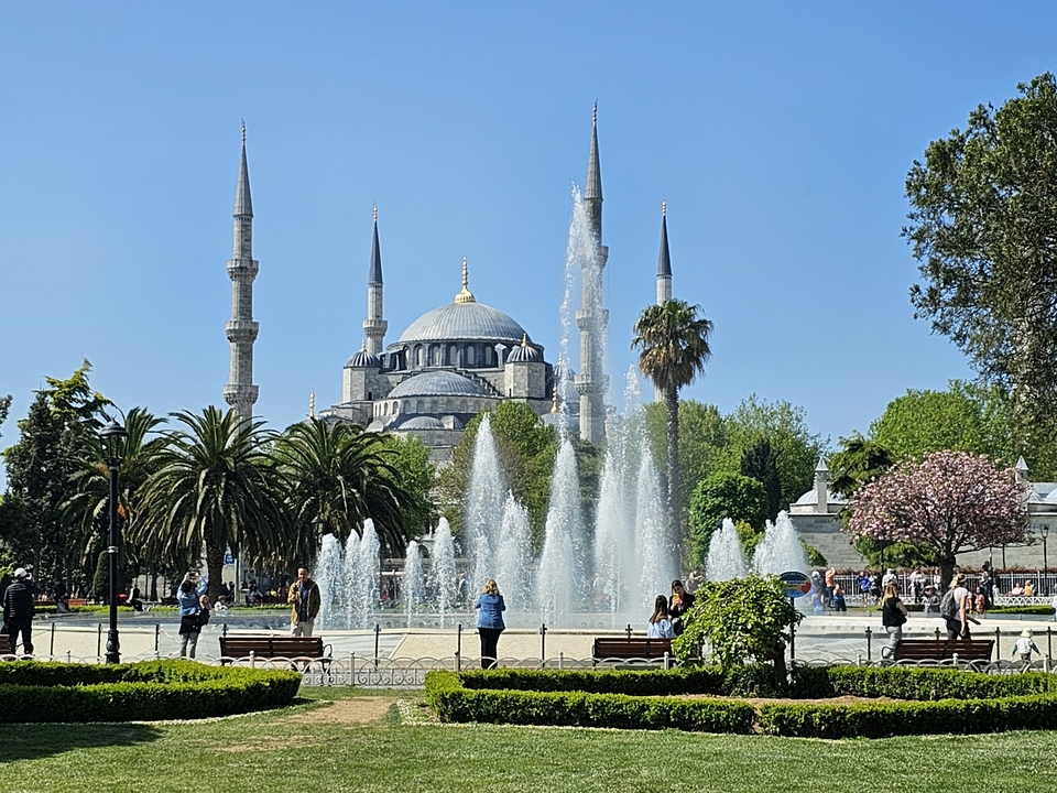 Des gens profitant d'un parc avec une mosquée en arrière-plan.