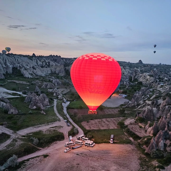 Montgolfière rouge vif dans un paysage rocheux.