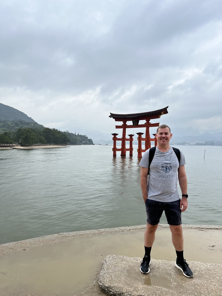 Personne debout devant un torii dans l'eau.