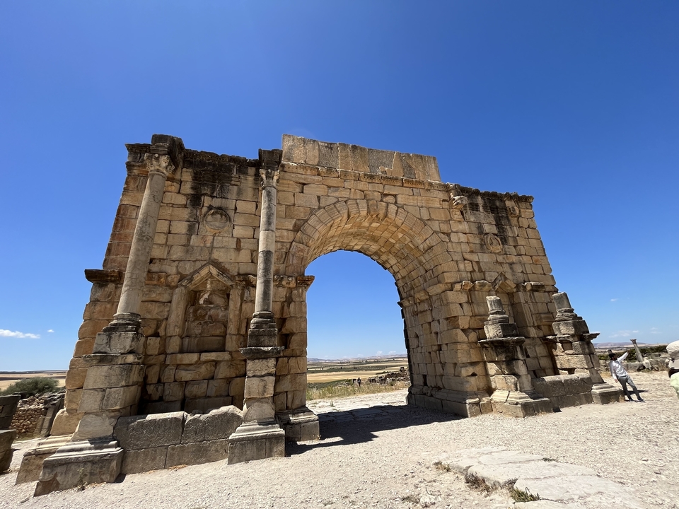 Ruins of an ancient Roman structure under a clear sky.