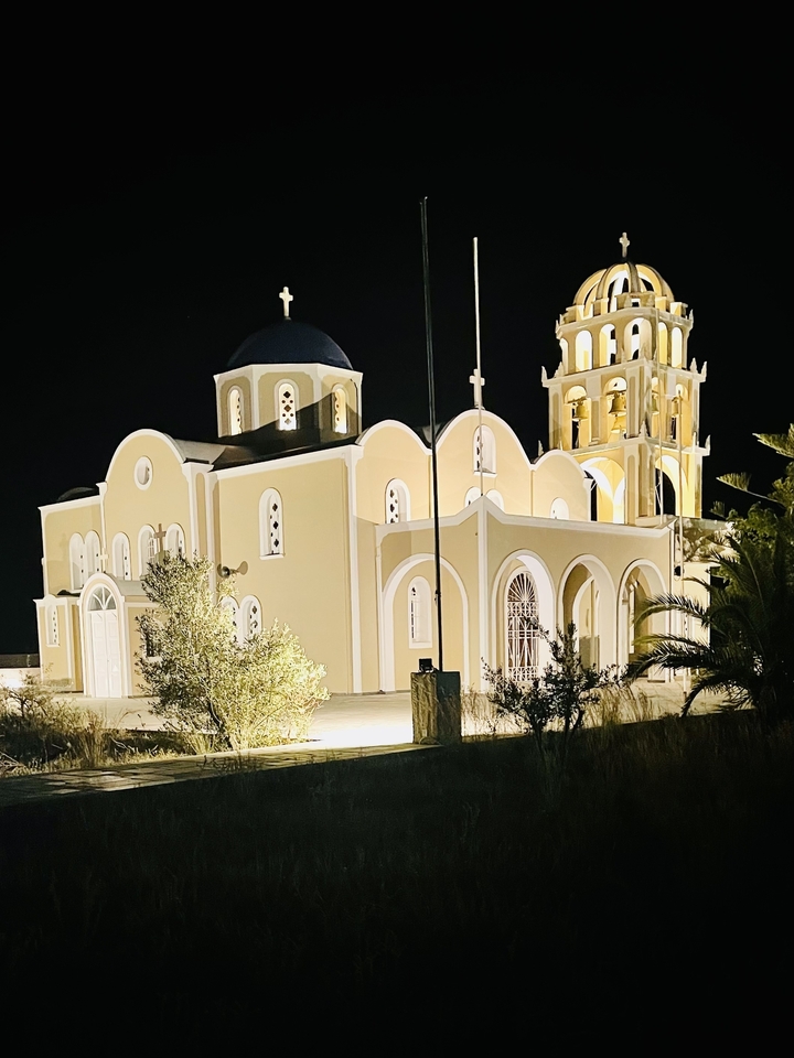 Church with arches and a tower at night, set against a clear sky.