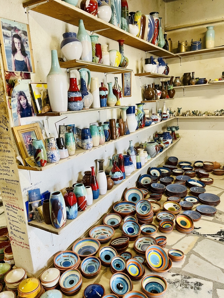Shop interior with colorful pottery on display shelves.