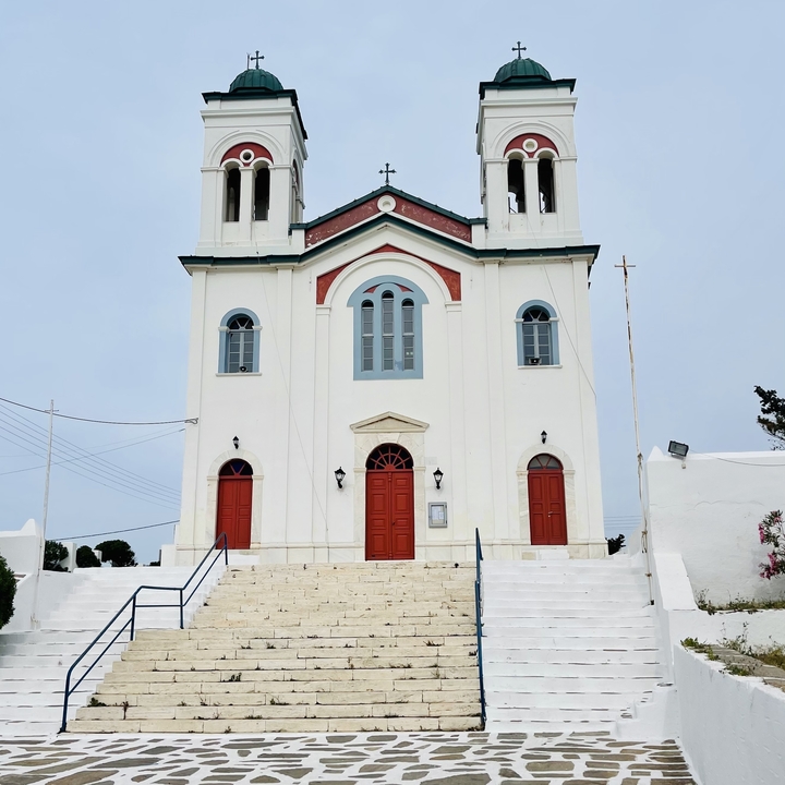 Facade of a church with red doors under a cloudy sky.