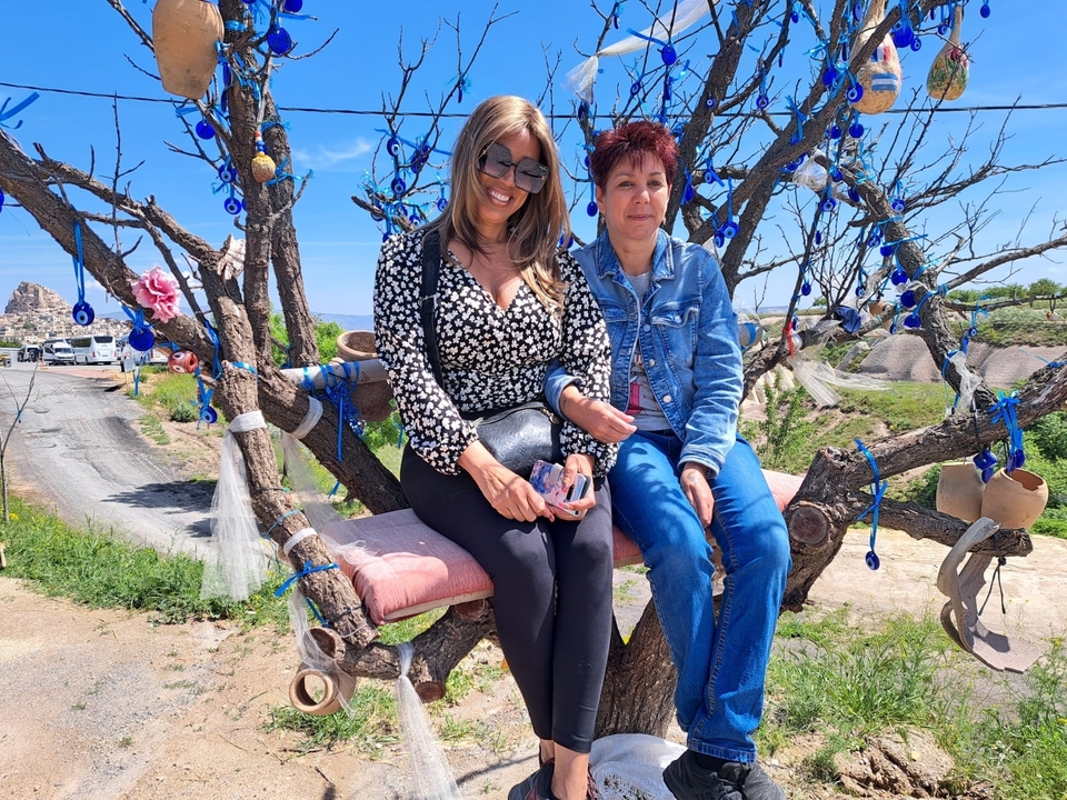 Two women sitting on a decorated tree swing, smiling.