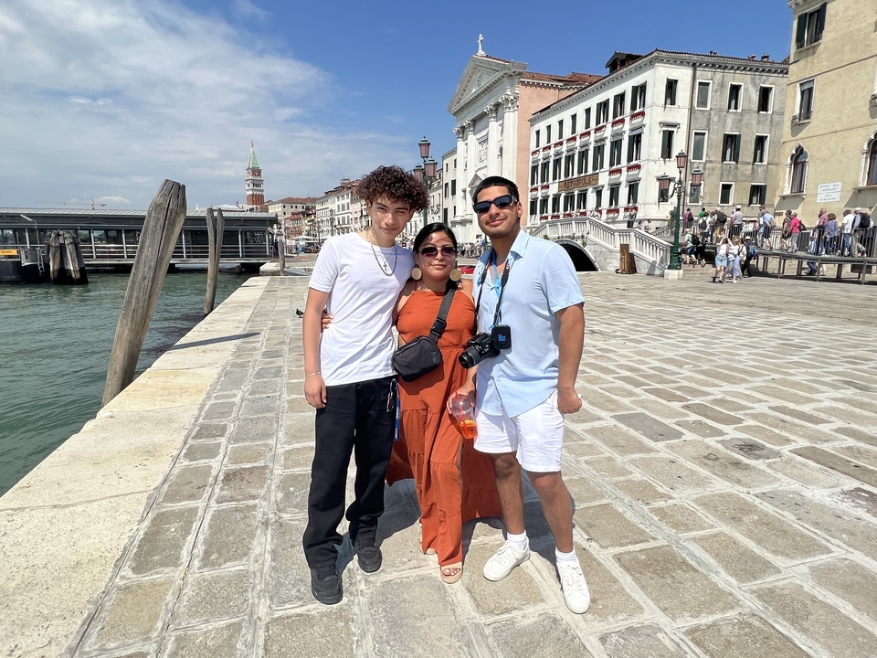 Three people posing on a waterfront in Venice.
