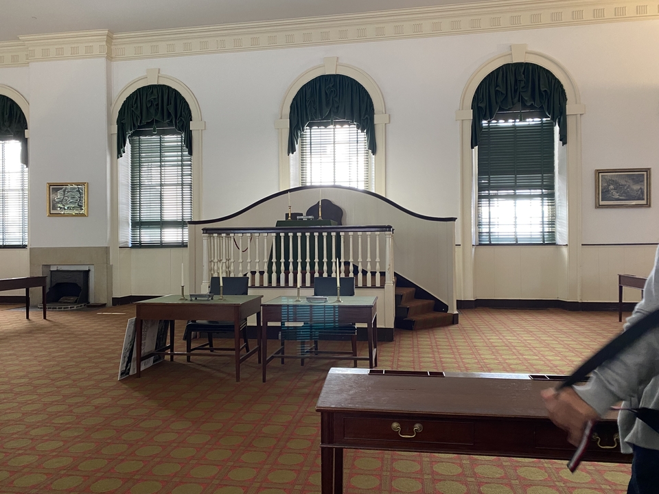 Salle de réunion historique avec bureaux et chaises.
