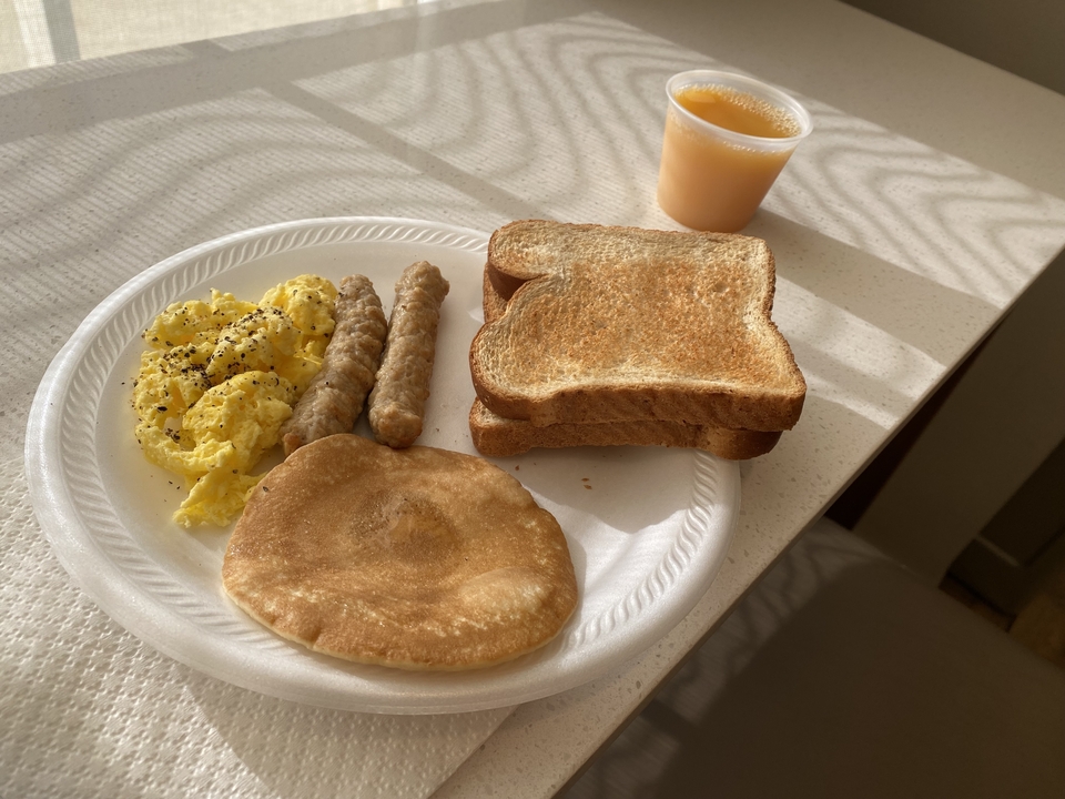 Plate with toast, scrambled eggs, sausage, and a pancake.