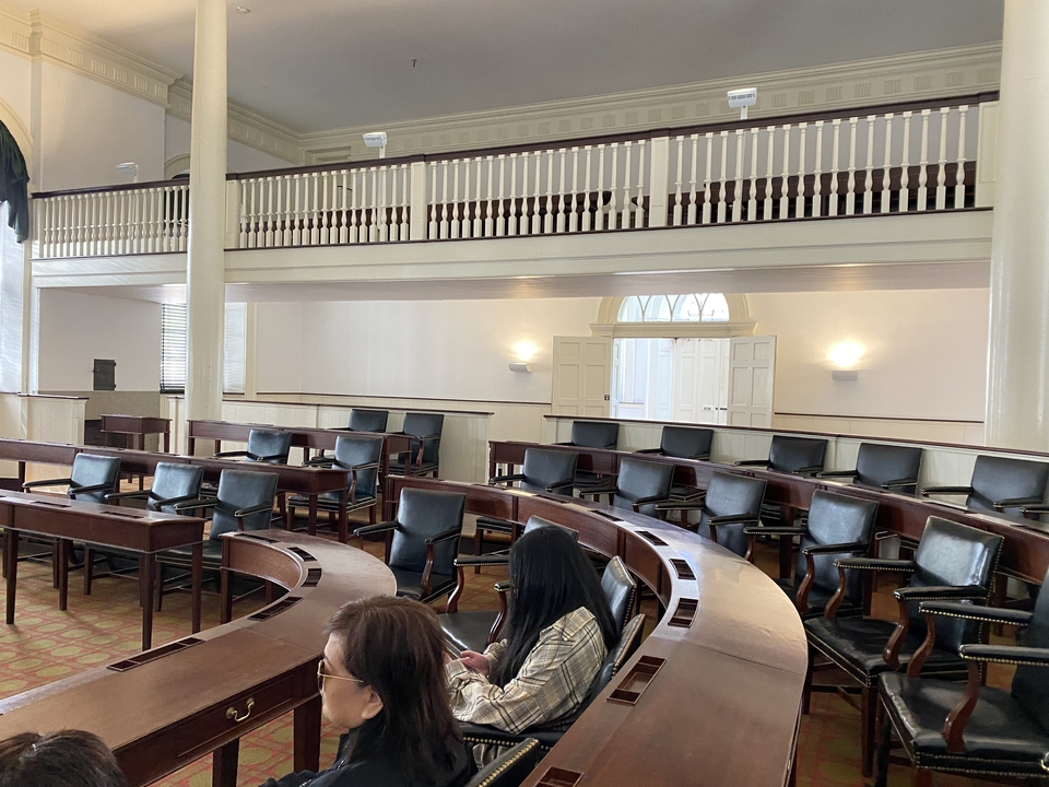 Salle d'assemblée historique avec sièges et pupitres incurvés.