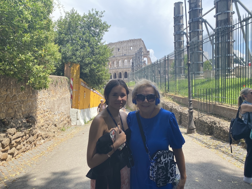 Two people posing near the Colosseum within a historic outdoor setting.