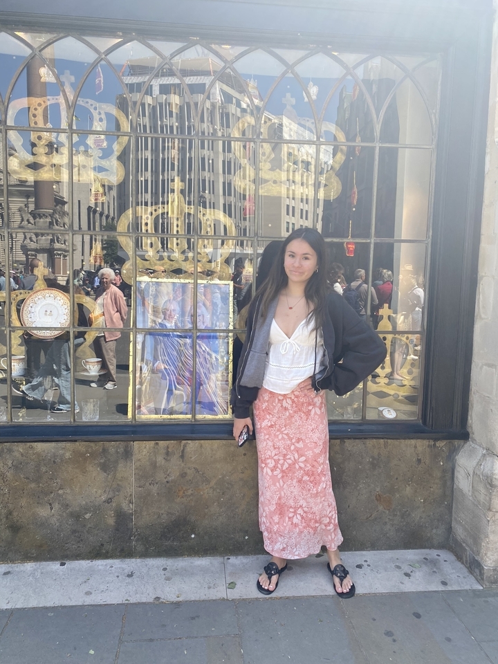 Person standing in front of a shop window displaying royal symbols.