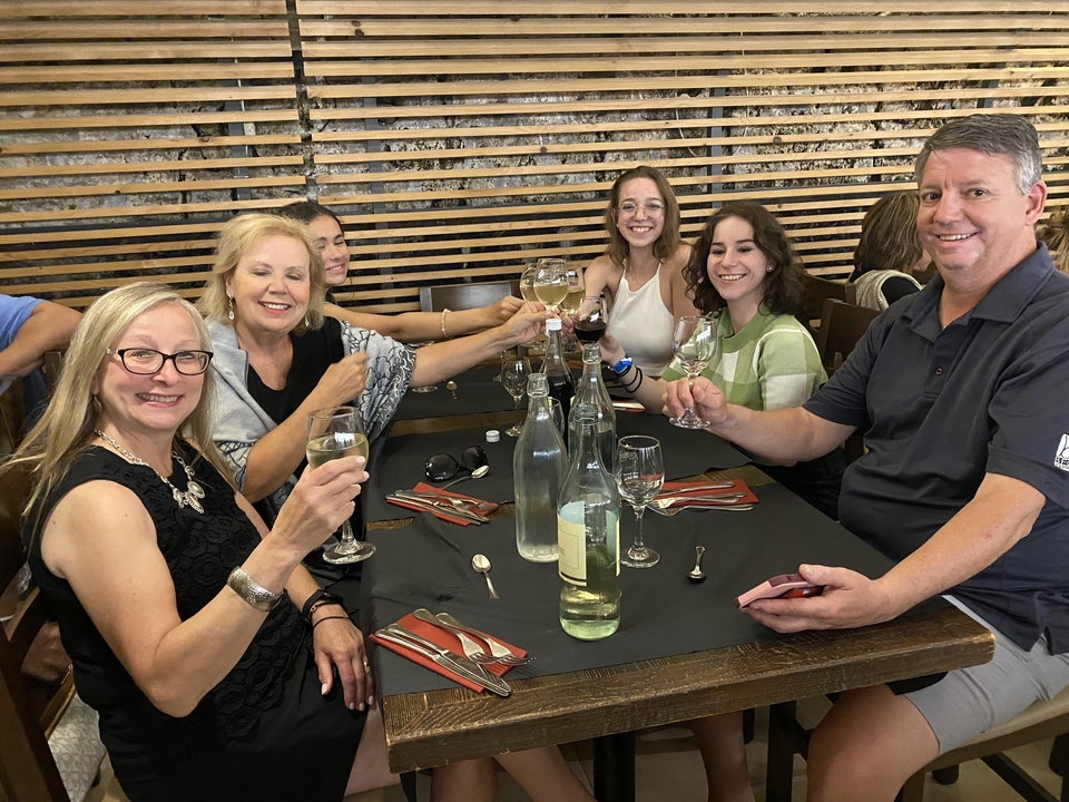 Group of diners raising glasses at an indoor restaurant table.