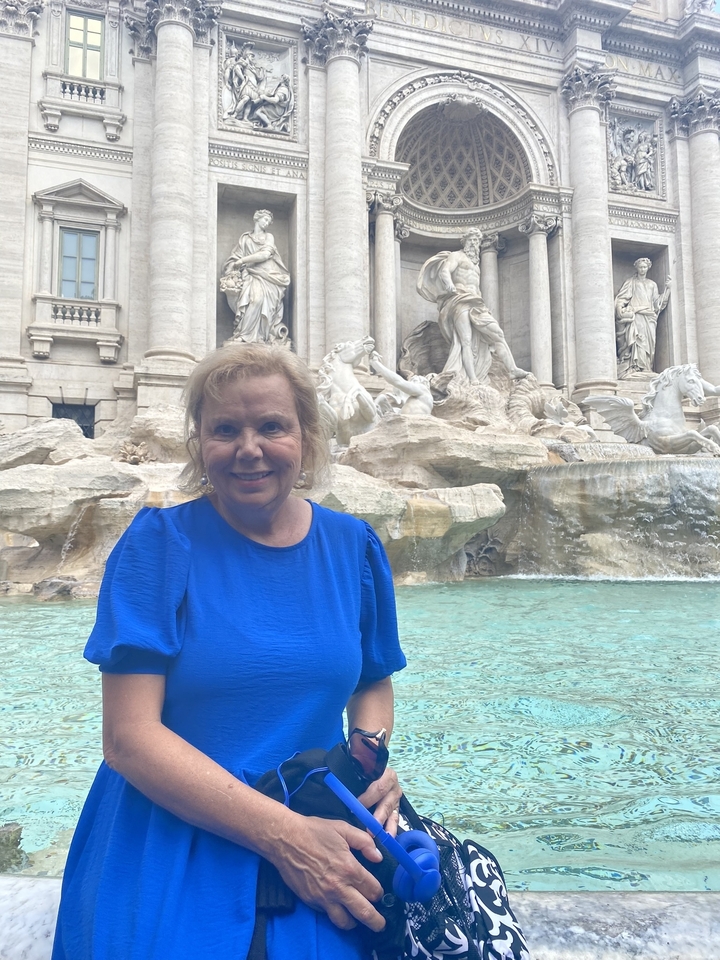 Person standing by the Trevi Fountain with baroque architecture in the background.